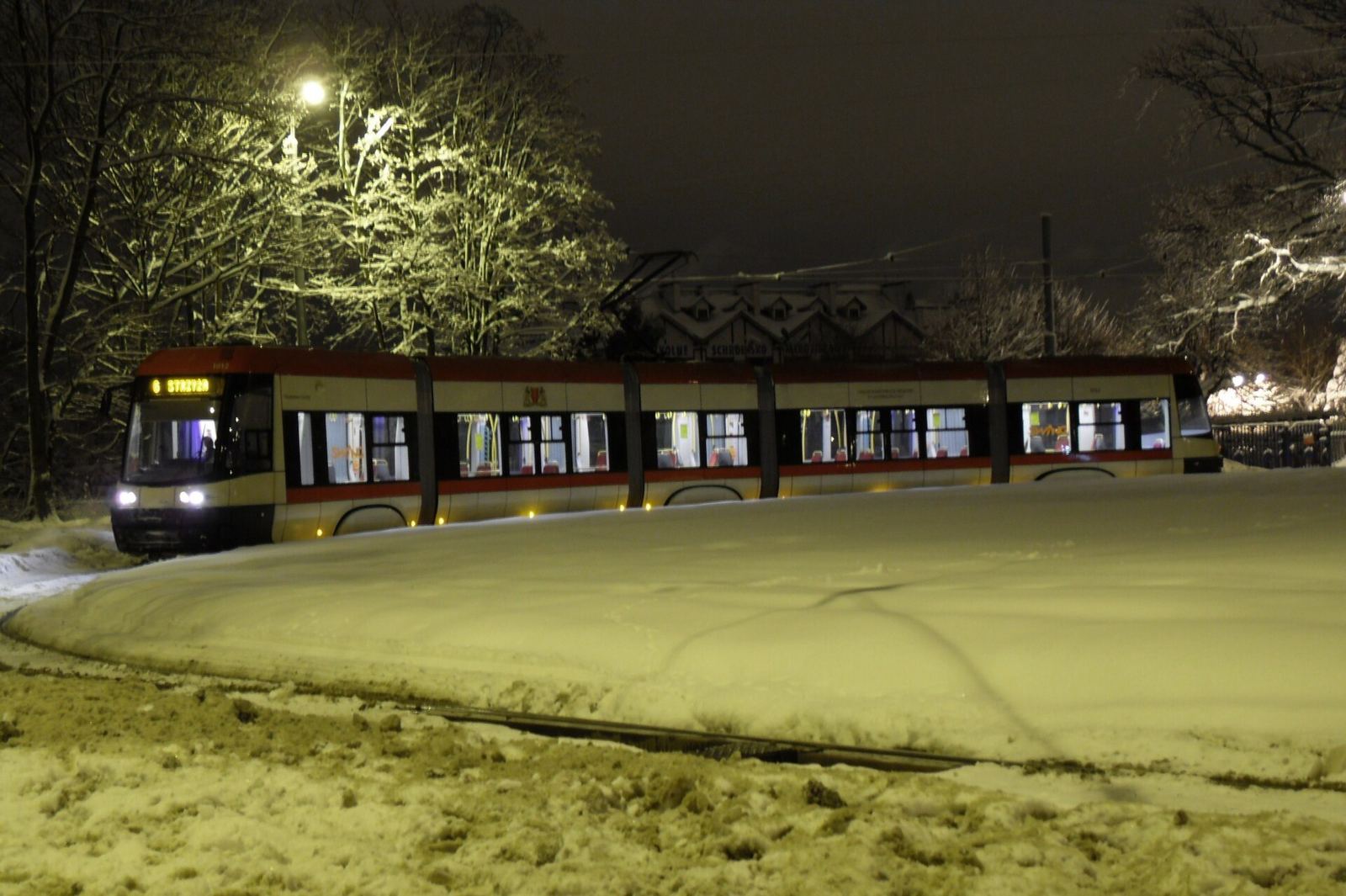 Tramwaj PESA w Gdańsku zimową nocą, śnieg na trawniku przy torowisku